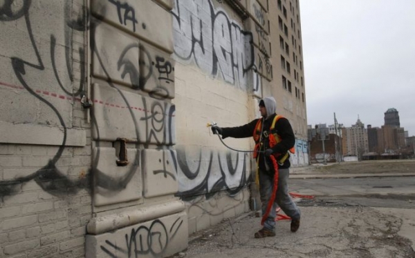 Laborer Brian Kuhn paints over graffiti on a blighted building near downtown Detroit in Detroit, Michigan, December 10, 2014