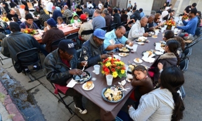 A child rests her head on the table as some homeless people have their lunch at the LA Mission&#039;s annual Thanksgiving meal.
