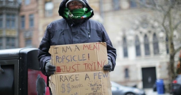 James Tocchio, who is homeless, holds up a sign as cold temperatures hit Boston this week. 